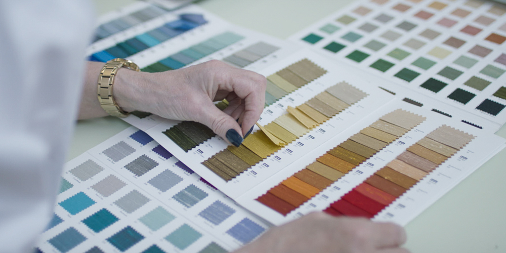 Close-up of hands selecting and browsing through colorful fabric swatches in a sample booklet.