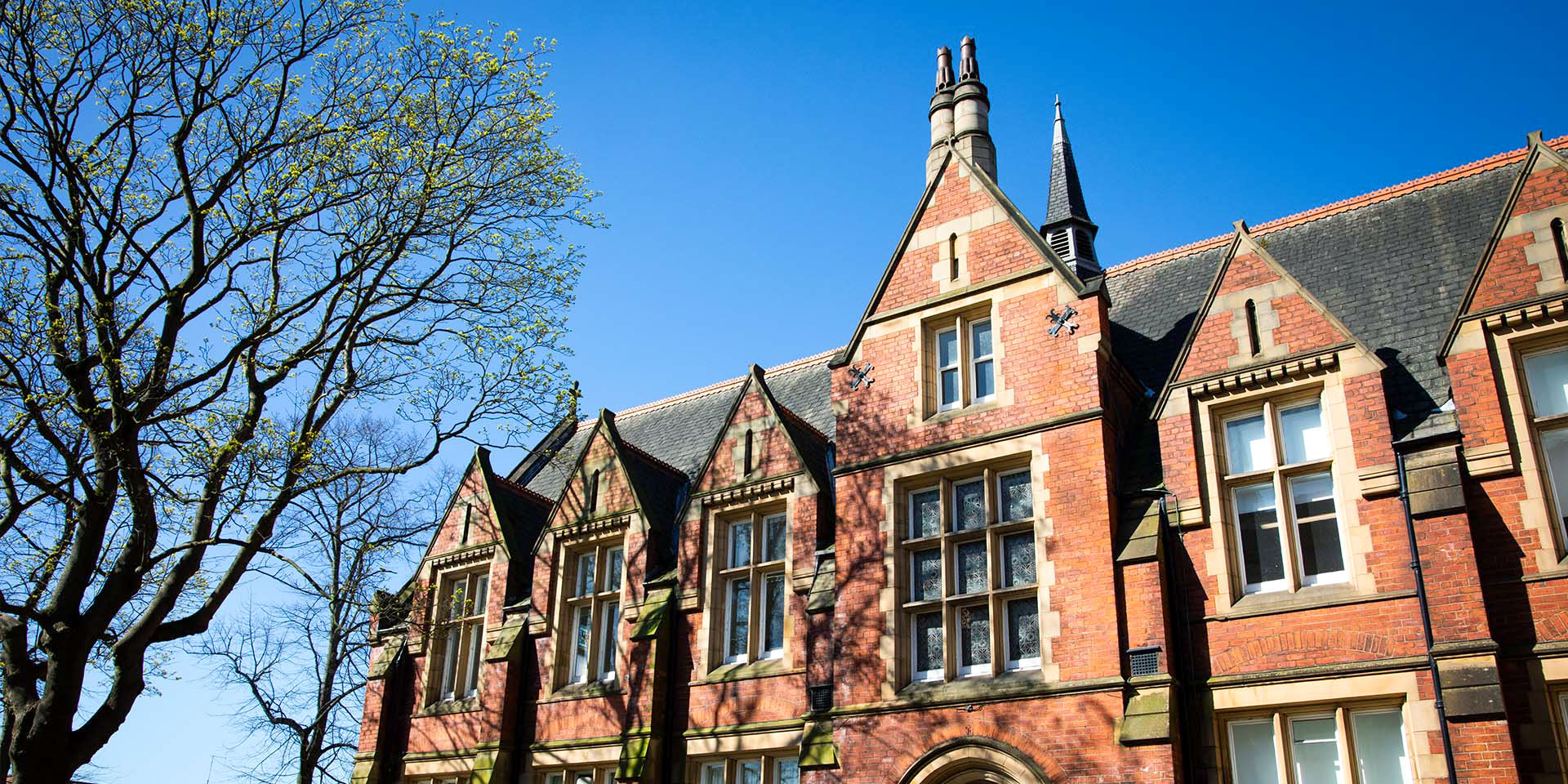 Low-angle view of a red brick Victorian-style university building facade.